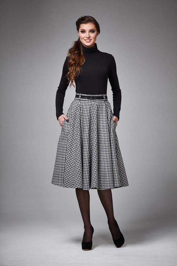 Beautiful young business woman with evening make-up wearing a skirt to the knee and a silk blouse with lace long sleeves and high-heeled shoes and a small black handbag, business clothes for meetings